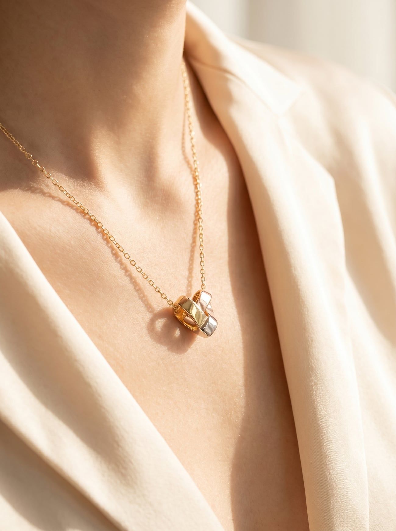 Der gefaltete Tri-Gold-Herzanhänger an einer feinen Goldkette auf dem Schlüsselbein einer Frau im warmen Abendlicht.